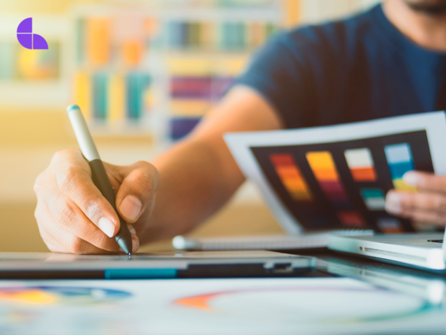 Graphic designer drawing whilst holding a colour palette.