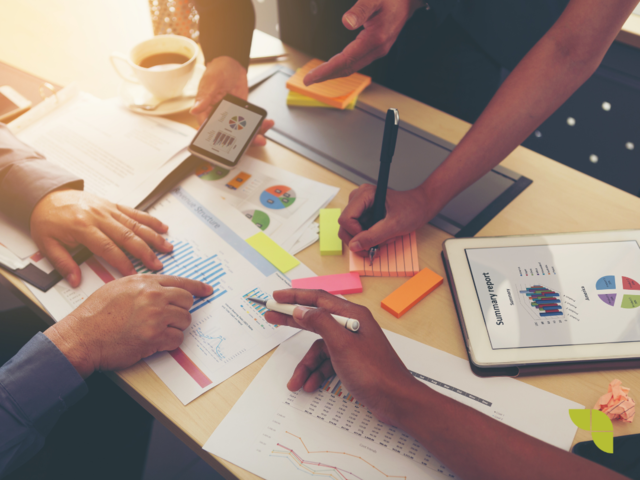 Group of data analysts looking at reports and discussing the findings.